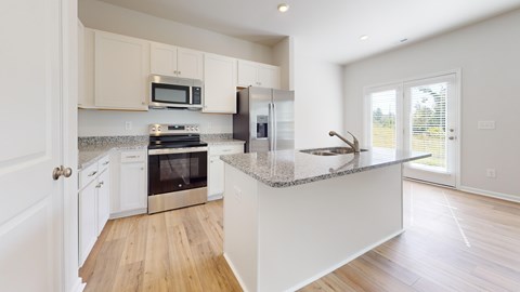 A modern kitchen with a granite countertop and stainless steel appliances.