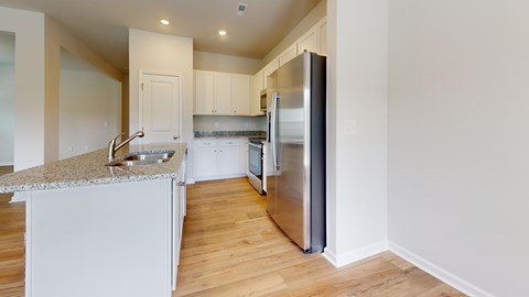 A kitchen with a refrigerator, sink, and cabinets.