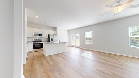 A spacious kitchen with wooden floors and white walls.