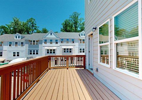 A wooden deck leads to a large white building with a balcony.