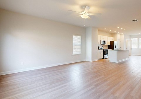 A spacious room with a ceiling fan and wooden flooring.