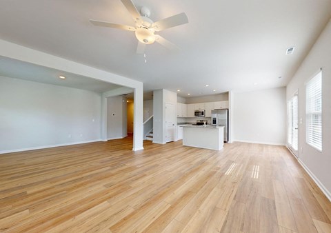 A spacious room with wooden flooring and a ceiling fan.