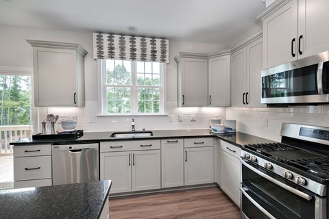 A kitchen with white cabinets and black countertops.