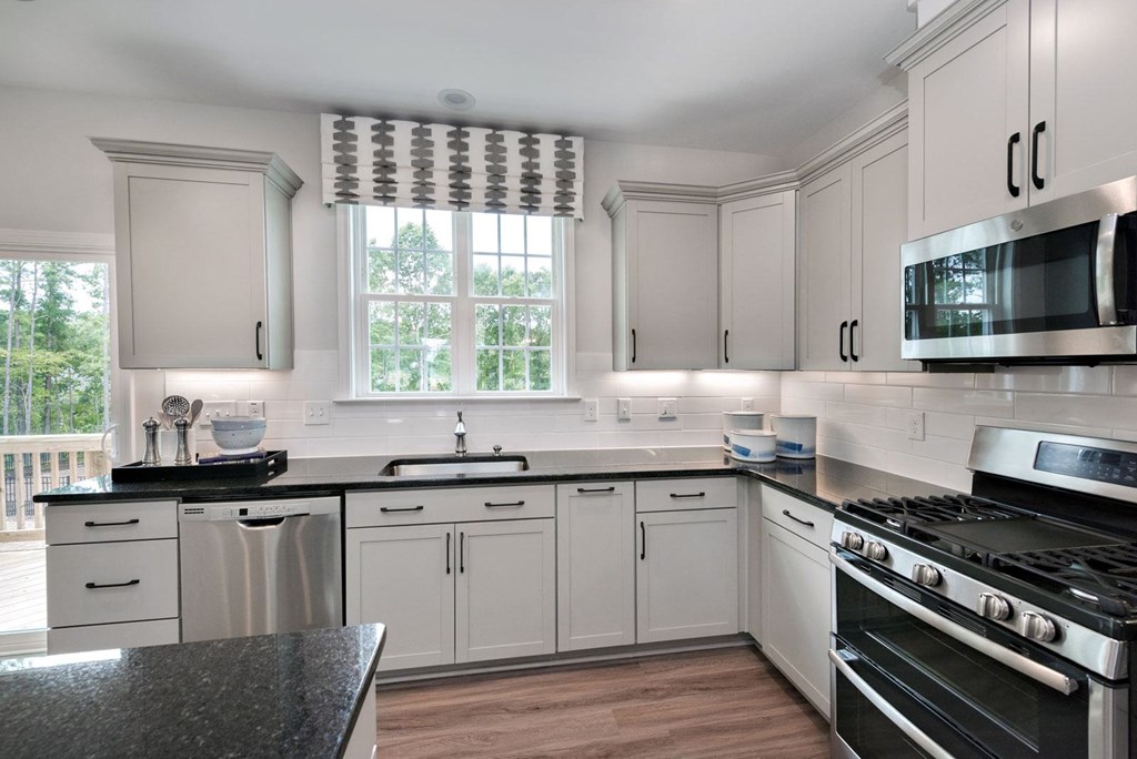 a kitchen with white cabinets and black counter tops