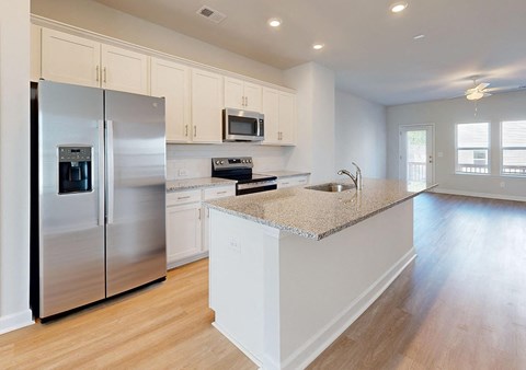 A modern kitchen with a granite countertop and stainless steel appliances.