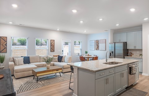 A modern kitchen and living room with a large island and a dining table.