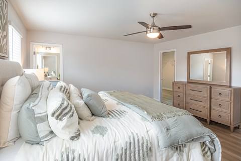 A bedroom with a bed, dresser, and mirror.