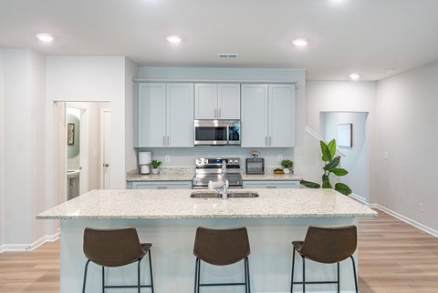 A kitchen with a granite countertop and bar stools.