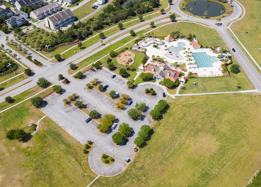 A large open grassy area with a parking lot and a pool.