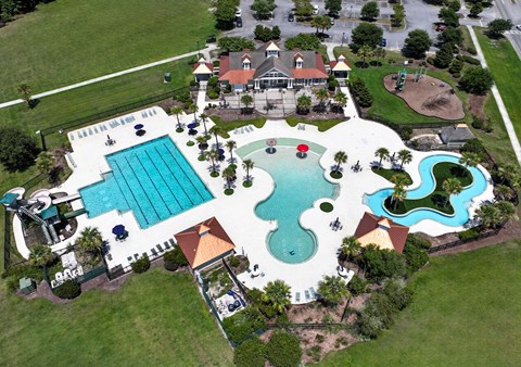 An aerial view of a resort with a large swimming pool and a water slide.