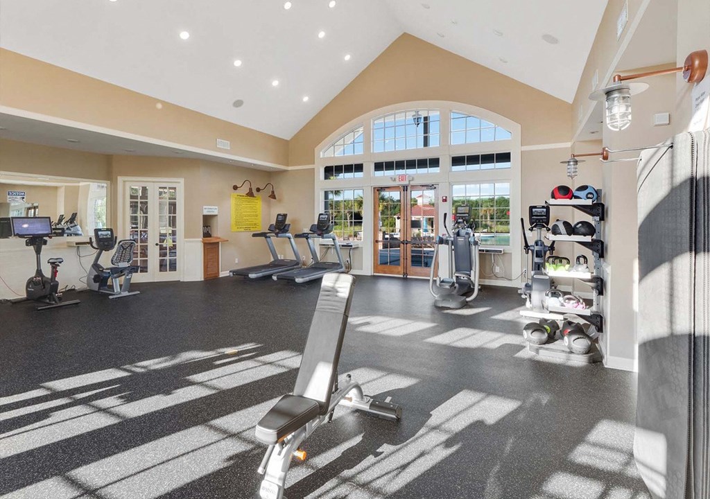 A gym with a variety of equipment including treadmills, weights, and exercise machines.