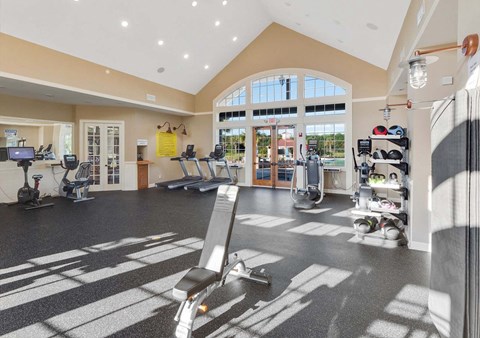 A gym with a variety of equipment including treadmills, weights, and exercise machines.