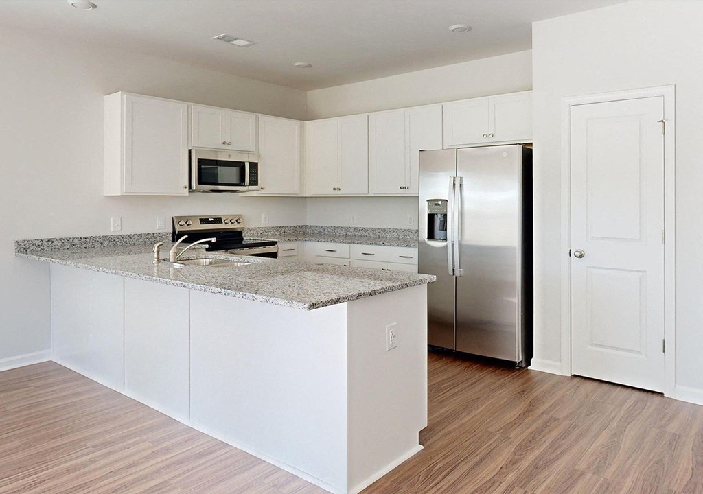 A kitchen with white cabinets and a granite countertop.