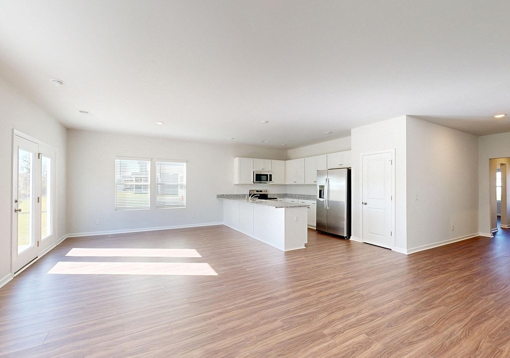 A spacious kitchen with white cabinets and a wooden floor.