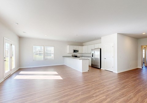 A spacious kitchen with white cabinets and a wooden floor.