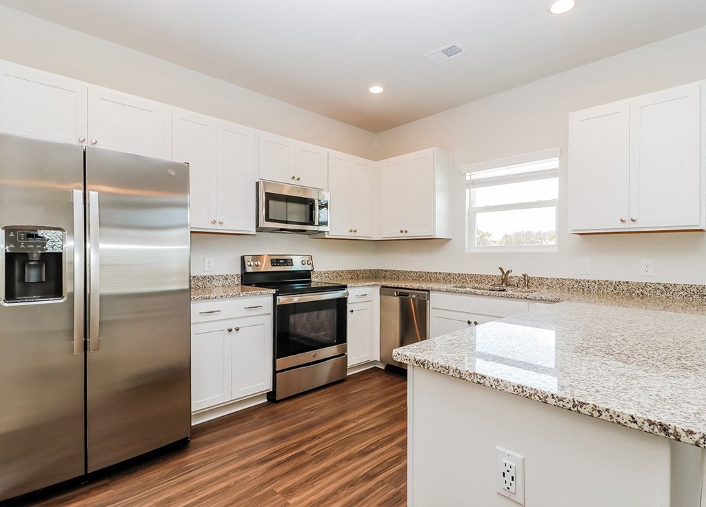 A kitchen with white cabinets and a granite counter.