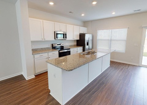 A kitchen with white cabinets and a granite countertop.
