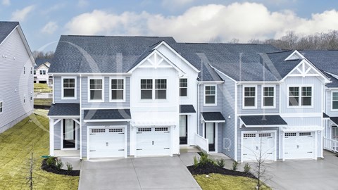 a white house with a gray roof and white garage doors