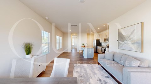 A spacious living room with a white couch and a large painting on the wall.