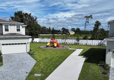 A backyard with a playground and a white fence.