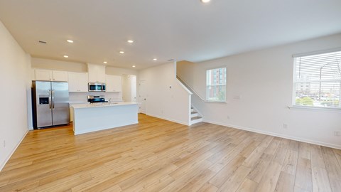 A spacious room with wooden flooring and a staircase leading to another level.