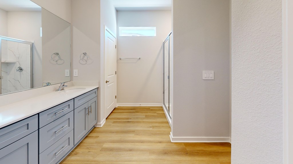 A bathroom with a white counter top and grey cabinets.