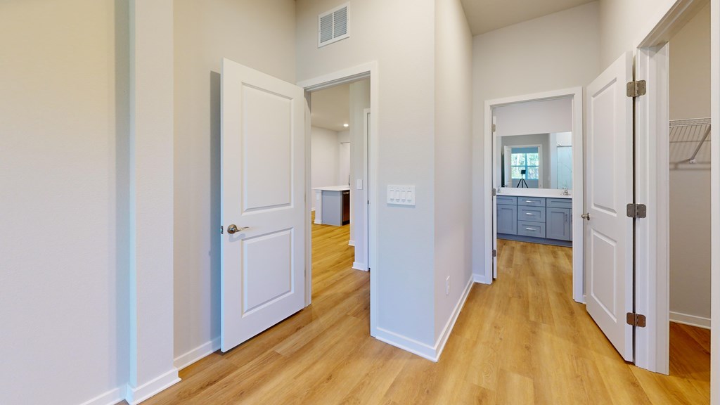 A hallway with white doors and wooden floors.