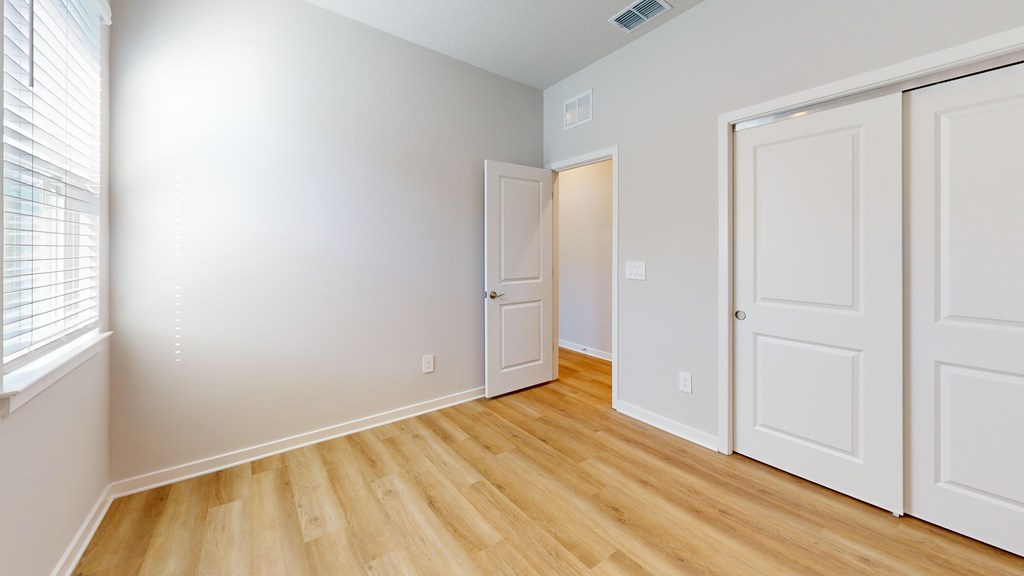 A room with white walls and wooden flooring with two doors.