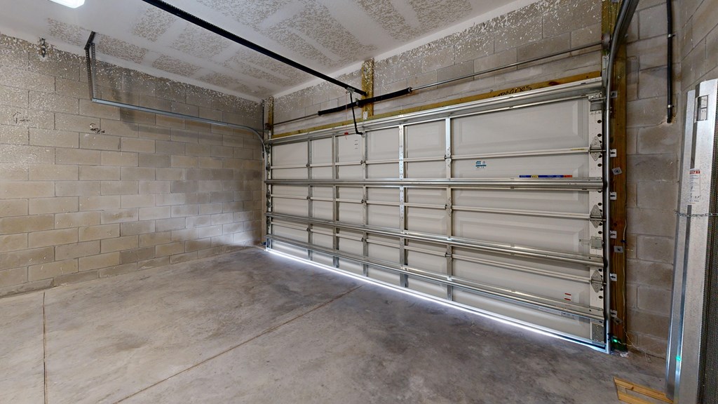 A garage with a closed white door and a concrete floor.