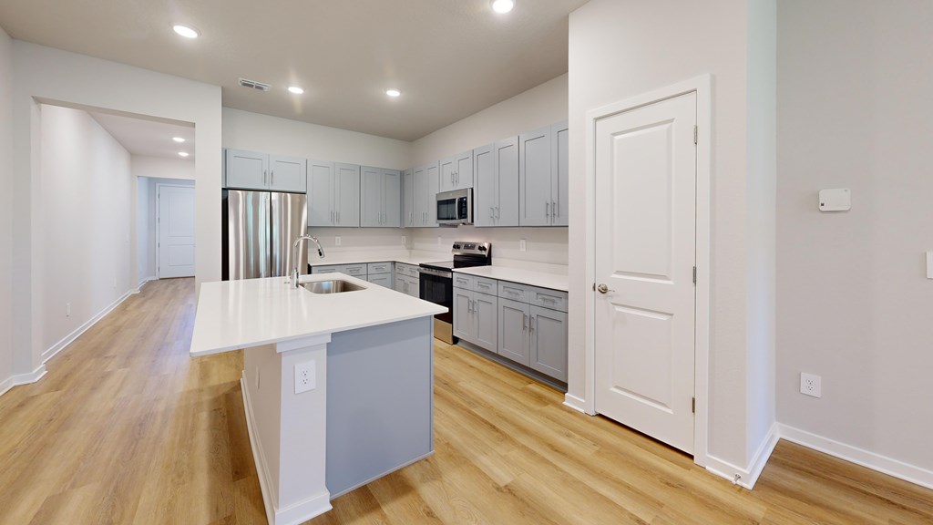 A kitchen with white cabinets and a white island.
