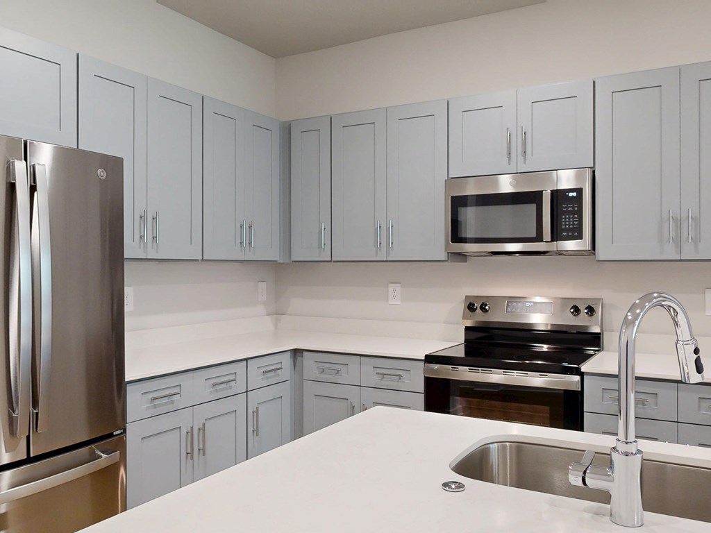A kitchen with a stainless steel refrigerator, microwave, oven, and sink.