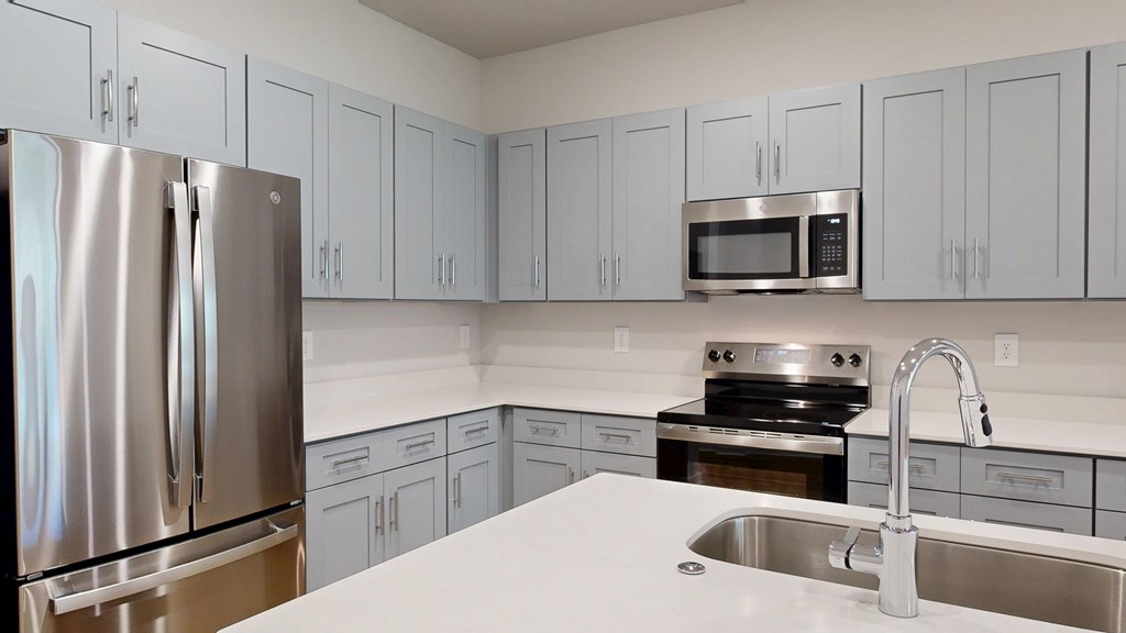 A kitchen with a stainless steel refrigerator and a white countertop.