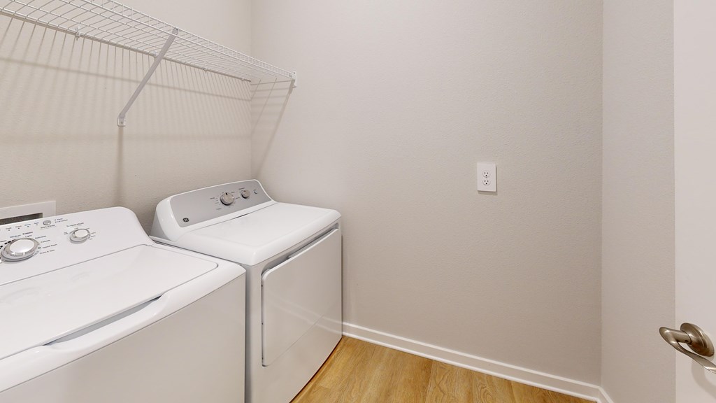 A white dryer and washer are sitting next to each other in a small laundry room.