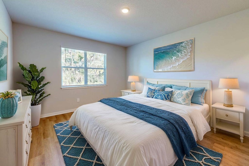 A bedroom with a large bed and a painting on the wall.