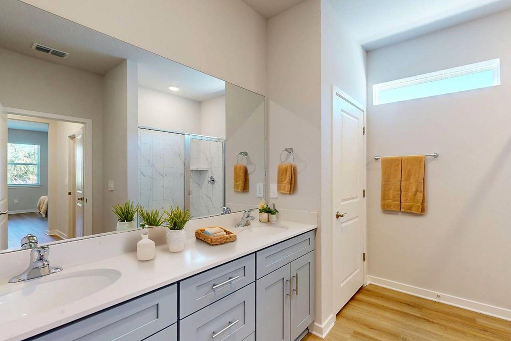 A bathroom with a white counter top and a large mirror.