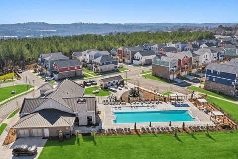 A large house with a pool in the foreground and a row of houses in the background.