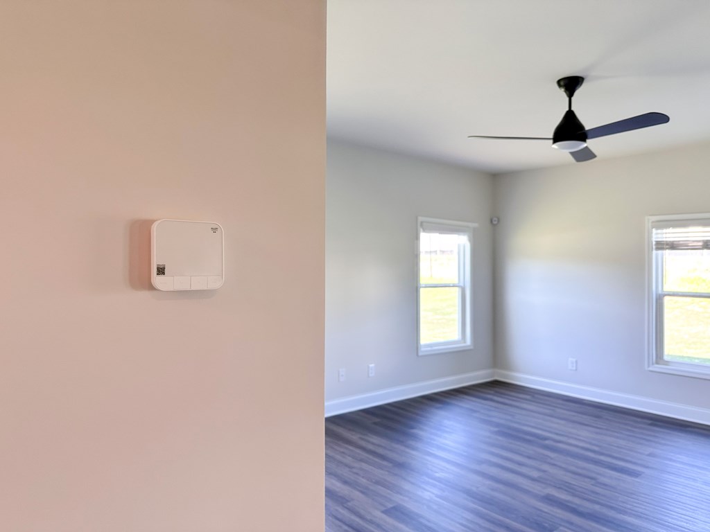 A room with a ceiling fan and a light switch on the wall.