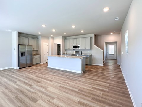 A kitchen with a white counter and wooden floors.