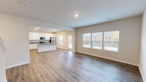 A spacious living room with hardwood floors and large windows.