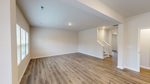 A spacious room with wooden floors and white walls.