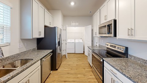 A kitchen with white cabinets and a black refrigerator.