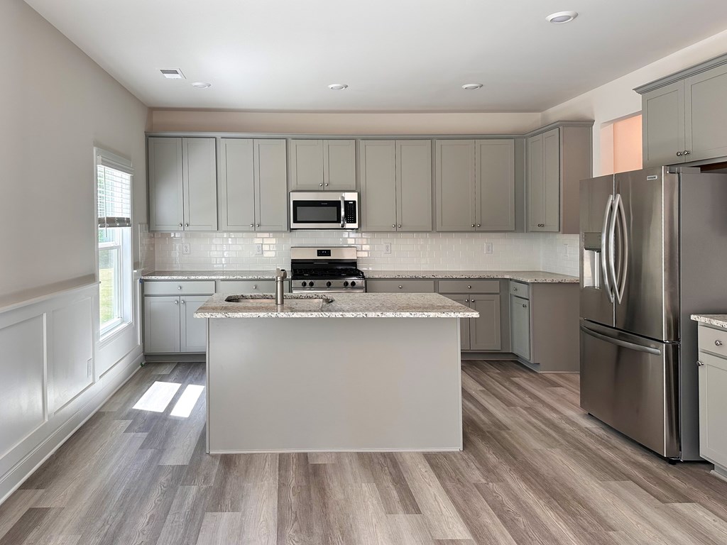 A modern kitchen with a large island and stainless steel appliances.