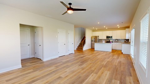 A spacious room with wooden floors and a ceiling fan.