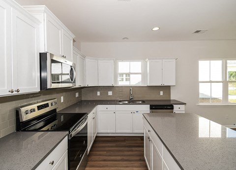 A modern kitchen with white cabinets and stainless steel appliances.