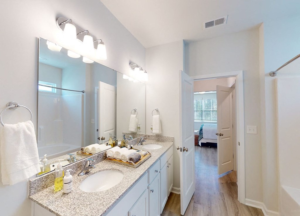 A bathroom with a double sink vanity and a large mirror above it.