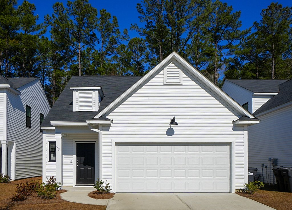 A white house with a black door and a garage door.