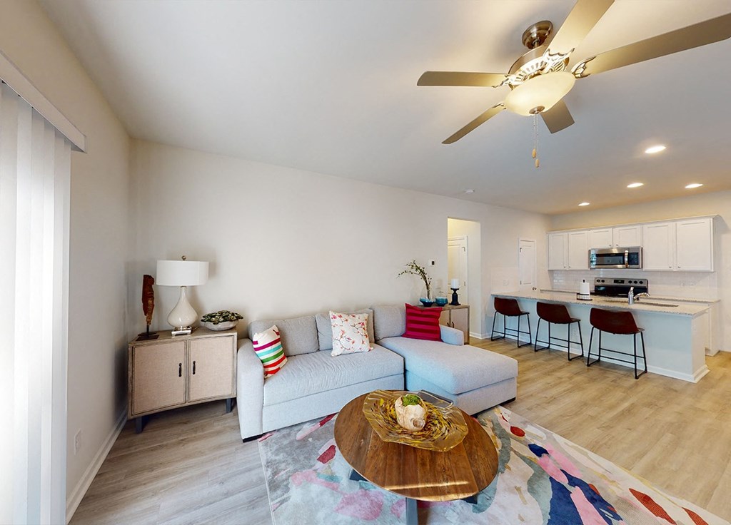 A living room with a couch, a coffee table, and a ceiling fan.