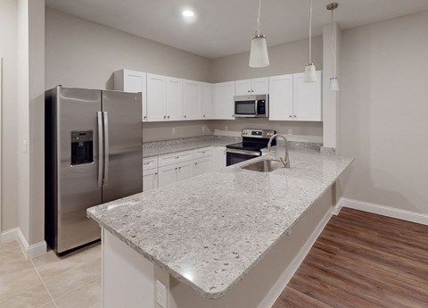 a kitchen with an island and stainless steel refrigerator