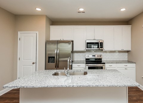 A kitchen with a granite countertop and stainless steel appliances.