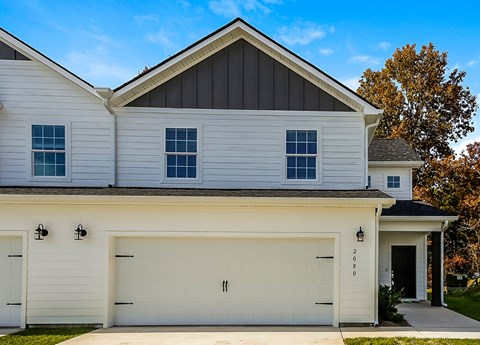 A modern house with a white garage door and a black roof.